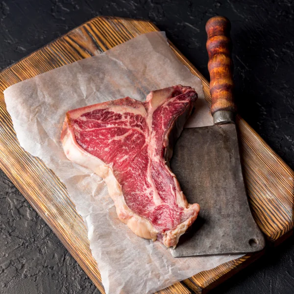 Steak de boeuf cru sur une planche à découper en bois avec un couteau à côté.