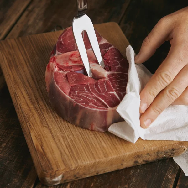Une personne découpe un morceau de viande avec un couteau sur une planche à découper.