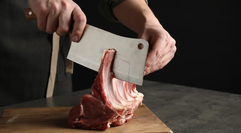 Une personne découpe de la viande avec un couteau sur une planche à découper.
