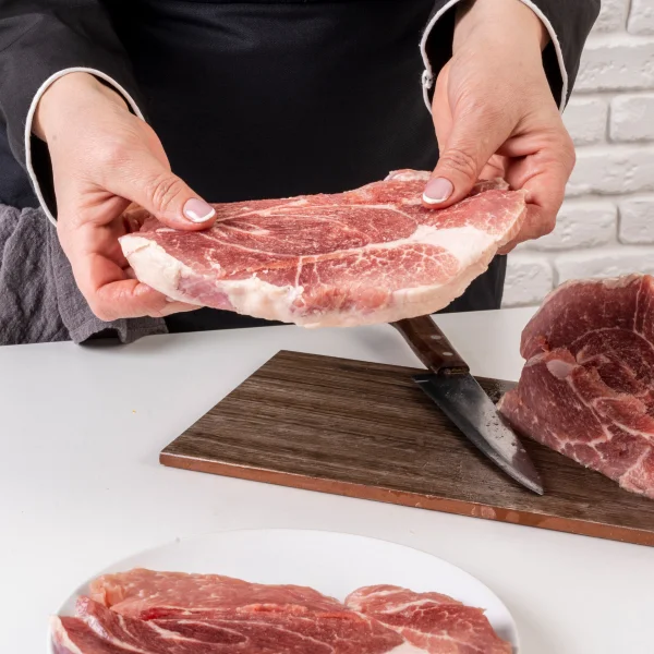 Une personne tient un morceau de viande sur une assiette.